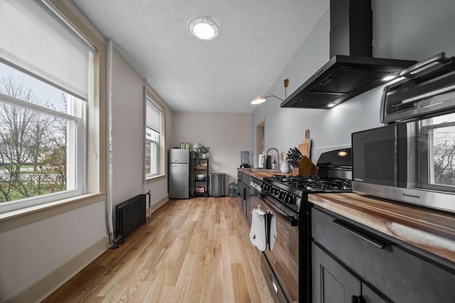 kitchen with radiator, plenty of natural light, stainless steel appliances, and range hood