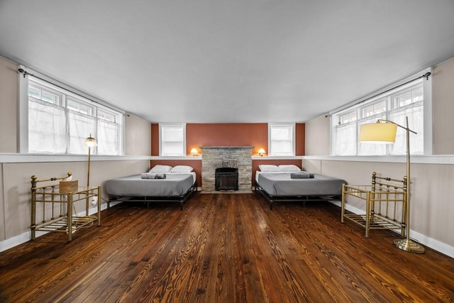 bedroom with dark hardwood / wood-style flooring and a stone fireplace