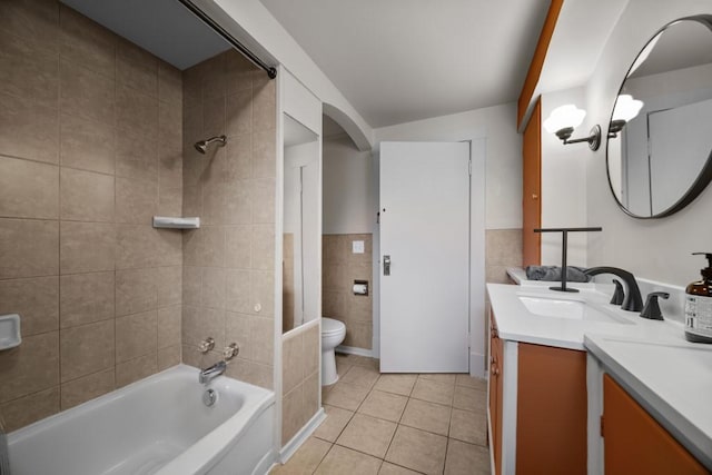 full bathroom featuring tile patterned floors, toilet, vanity, tile walls, and tiled shower / bath