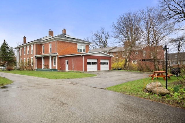 view of side of property with a lawn, a garage, and solar panels