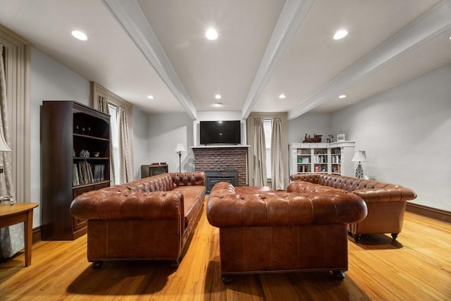 living room featuring a fireplace, beamed ceiling, and light wood-type flooring