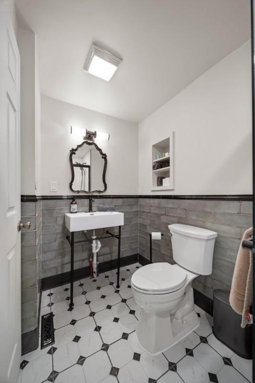 bathroom with toilet and tile walls