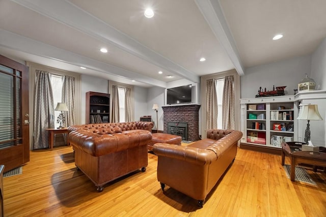 living room with beamed ceiling, light hardwood / wood-style flooring, and a fireplace