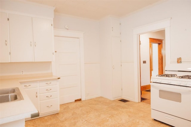 kitchen with white gas range, crown molding, sink, and white cabinets