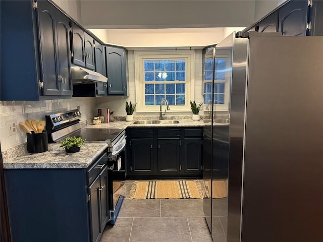 kitchen featuring sink, light stone counters, dark tile patterned floors, decorative backsplash, and appliances with stainless steel finishes