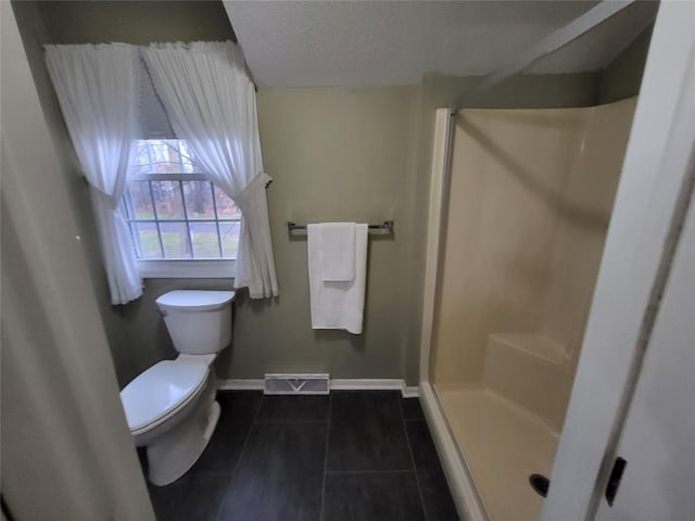 bathroom featuring a shower, a textured ceiling, toilet, and tile patterned flooring