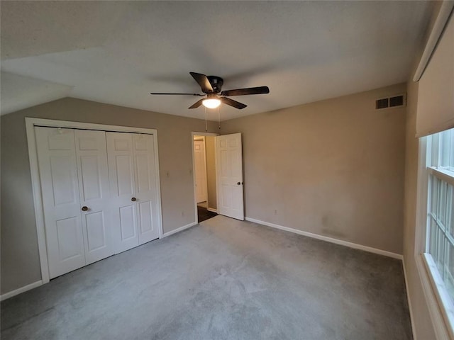 unfurnished bedroom with ceiling fan, lofted ceiling, carpet floors, and a closet