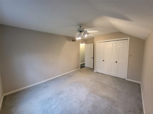 unfurnished bedroom featuring carpet flooring, ceiling fan, a closet, and vaulted ceiling