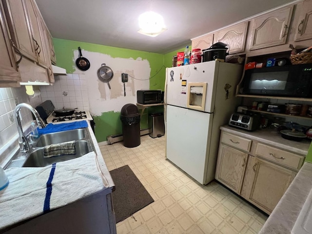 kitchen with gas stove, sink, a baseboard radiator, white fridge with ice dispenser, and decorative backsplash