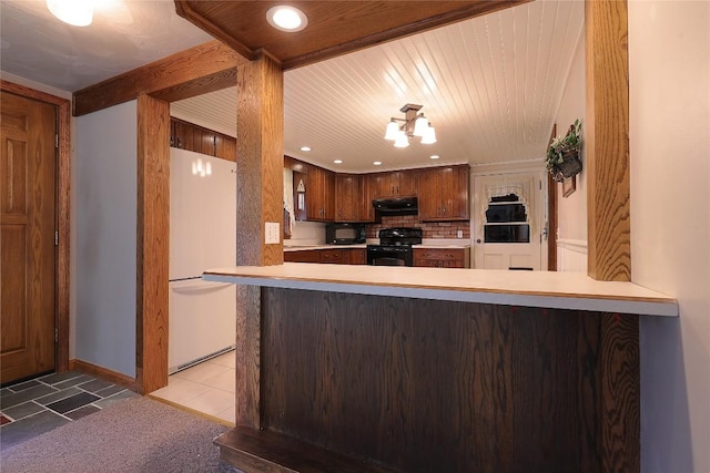 kitchen with kitchen peninsula, white fridge, black range oven, and exhaust hood