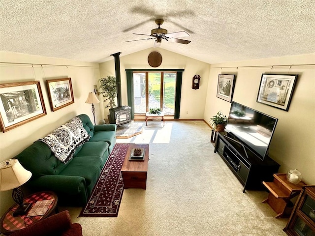 living room featuring lofted ceiling, a wood stove, light carpet, ceiling fan, and a textured ceiling