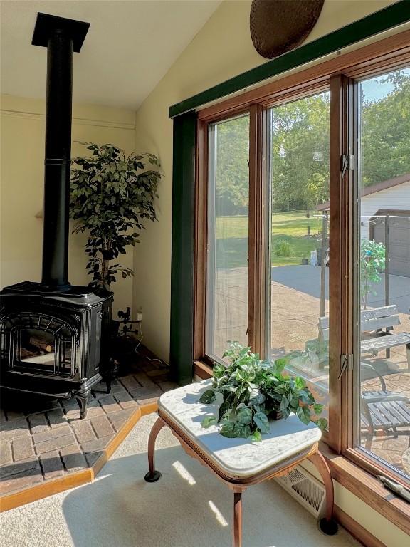 interior space featuring a wood stove, a wealth of natural light, and vaulted ceiling