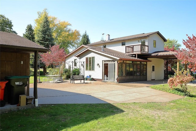 rear view of house with a yard, a balcony, a patio area, and a sunroom