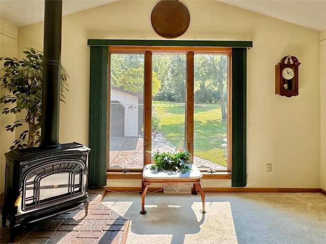 doorway to outside featuring a wood stove, a wealth of natural light, and lofted ceiling