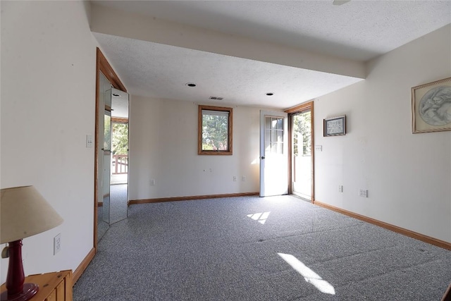 unfurnished room featuring carpet flooring, a healthy amount of sunlight, and a textured ceiling