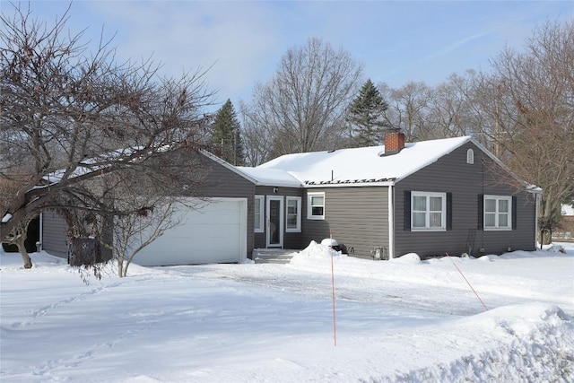 snow covered rear of property with a garage