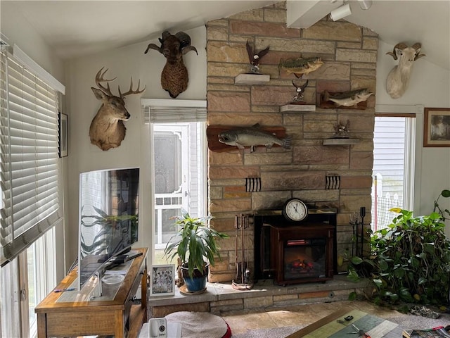 living room featuring a stone fireplace and vaulted ceiling