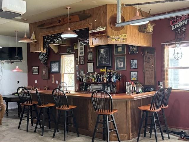 bar featuring wooden walls and decorative light fixtures