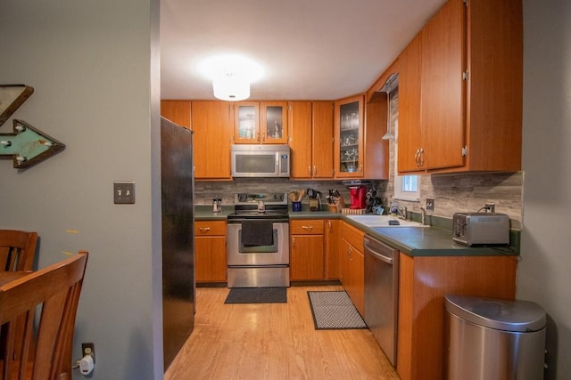 104 Hillcrest Dr, Edinboro, PA 16412 - kitchen featuring stainless steel appliances, light wood-style floors, a sink, brown cabinets, and tasteful backsplash