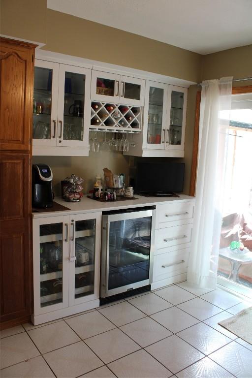 bar featuring white cabinets, light tile patterned floors, and wine cooler