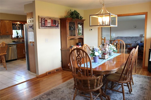 dining room featuring a notable chandelier, light wood-type flooring, and sink