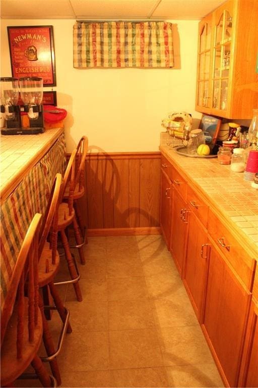 kitchen featuring tile countertops and wooden walls