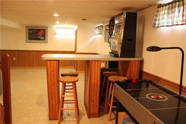 bar with a paneled ceiling and wood walls