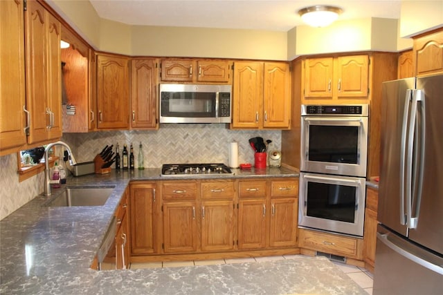 kitchen featuring dark stone counters, sink, light tile patterned floors, tasteful backsplash, and stainless steel appliances