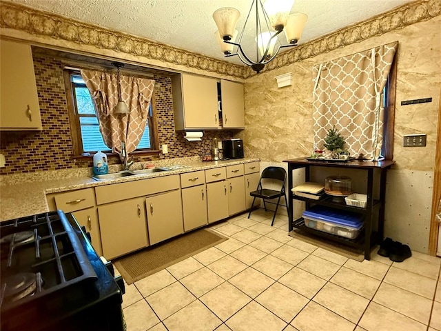 kitchen with black stove, sink, a notable chandelier, cream cabinetry, and light tile patterned floors