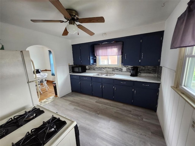 3829 Parade Blvd, Erie, PA 16504 - kitchen featuring blue cabinetry, a sink, white appliances, arched walkways, and healthy amount of natural light