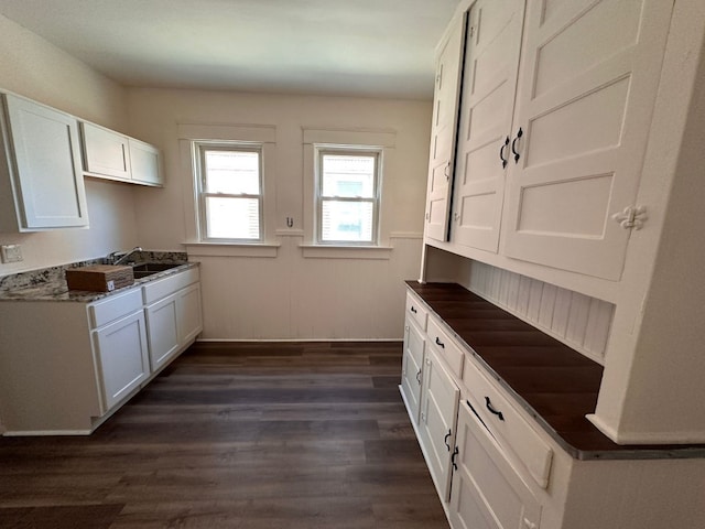 kitchen with dark hardwood / wood-style flooring, white cabinetry, sink, and dark stone counters