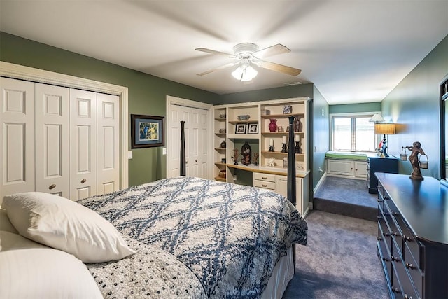 bedroom with ceiling fan, dark carpet, and two closets