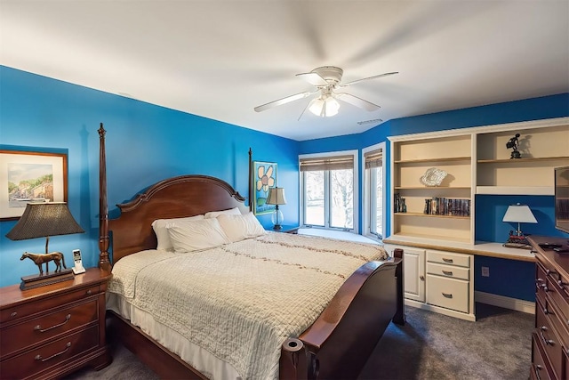 bedroom with ceiling fan, visible vents, dark colored carpet, and built in desk