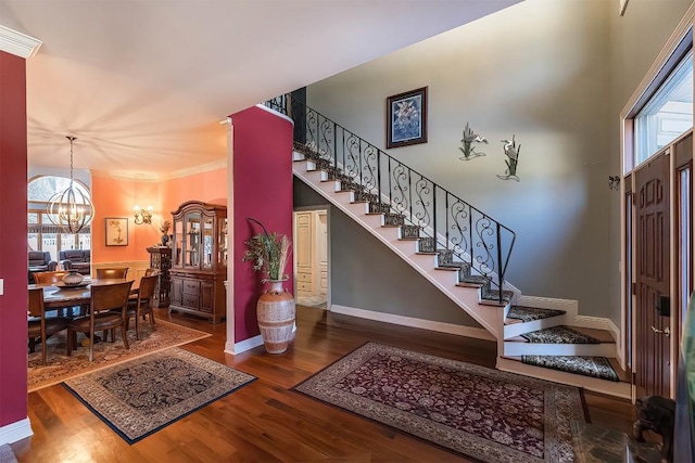 foyer entrance with wood finished floors, baseboards, stairway, an inviting chandelier, and crown molding