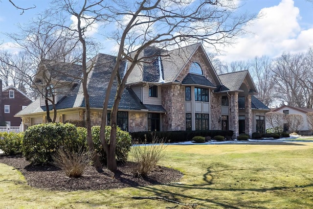 view of front facade with a garage, stone siding, and a front yard