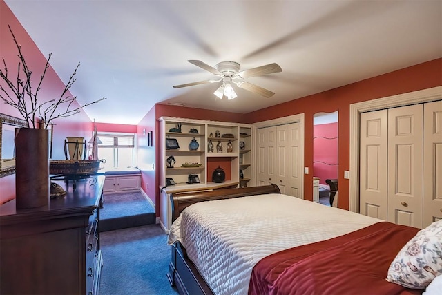 bedroom with a ceiling fan, dark colored carpet, and two closets