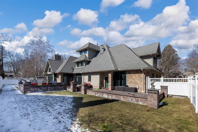 rear view of house featuring stone siding, a patio area, a yard, and a fenced backyard