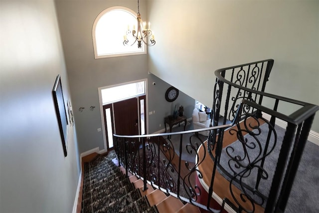 foyer entrance with a chandelier, a towering ceiling, and baseboards