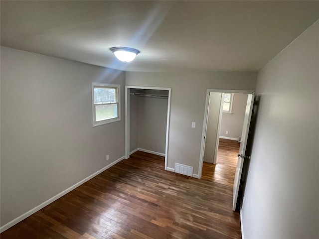 unfurnished bedroom featuring dark hardwood / wood-style flooring and a closet