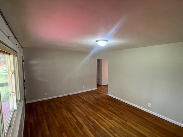 empty room featuring a textured ceiling and dark hardwood / wood-style floors