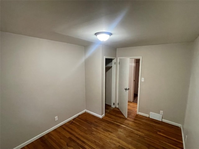 unfurnished bedroom featuring dark hardwood / wood-style flooring, a spacious closet, and a closet