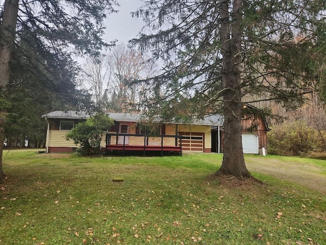 rear view of house with a yard, a garage, and a wooden deck