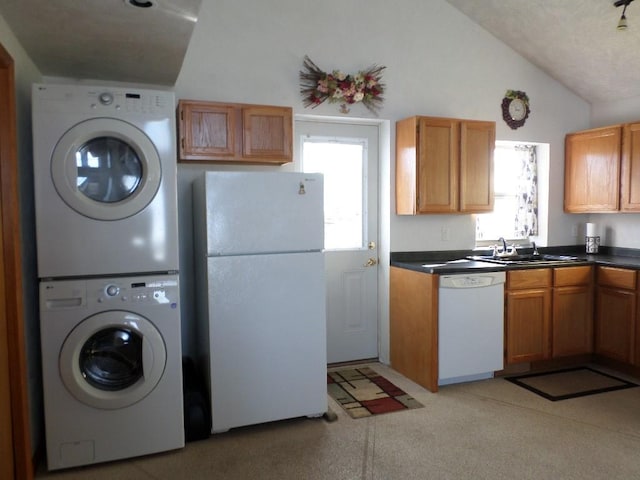 kitchen featuring stacked washing maching and dryer, vaulted ceiling, sink, and white appliances