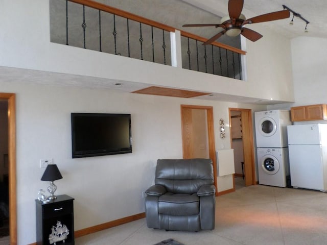 living room featuring a high ceiling, stacked washer and clothes dryer, track lighting, and ceiling fan