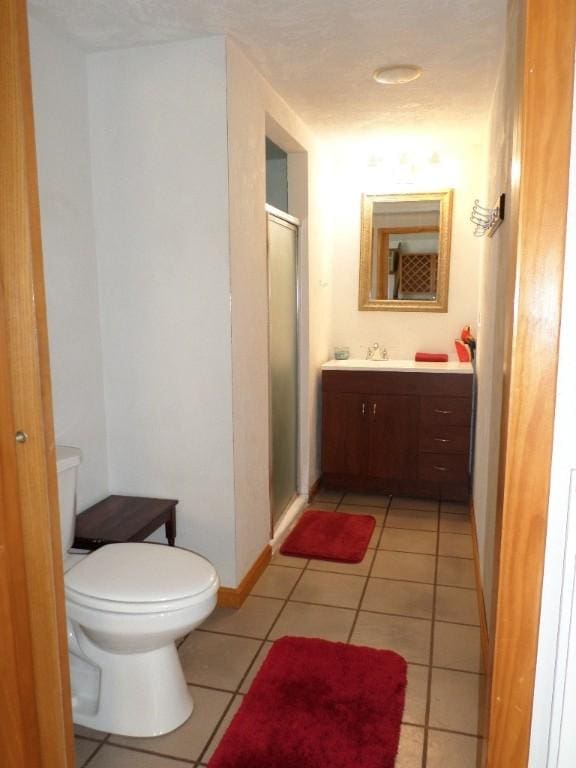 bathroom featuring tile patterned flooring, vanity, an enclosed shower, and toilet