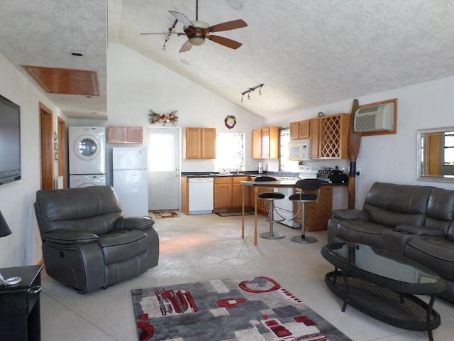 living room with stacked washing maching and dryer, a wall mounted AC, high vaulted ceiling, and a wealth of natural light