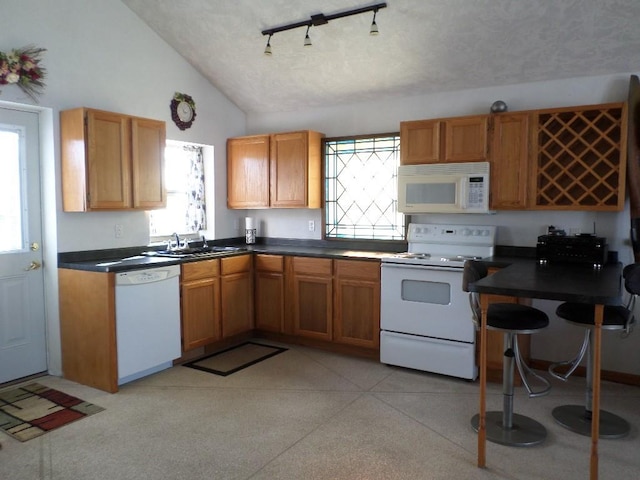 kitchen featuring sink, white appliances, vaulted ceiling, and a textured ceiling