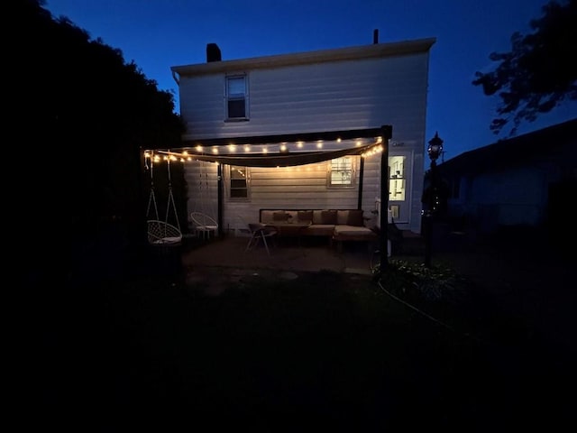 3322 Parade St, Erie, PA 16504 - back of house at night with a patio, an outdoor hangout area, and a chimney