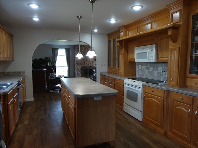 kitchen featuring a center island, white appliances, sink, a fireplace, and decorative light fixtures