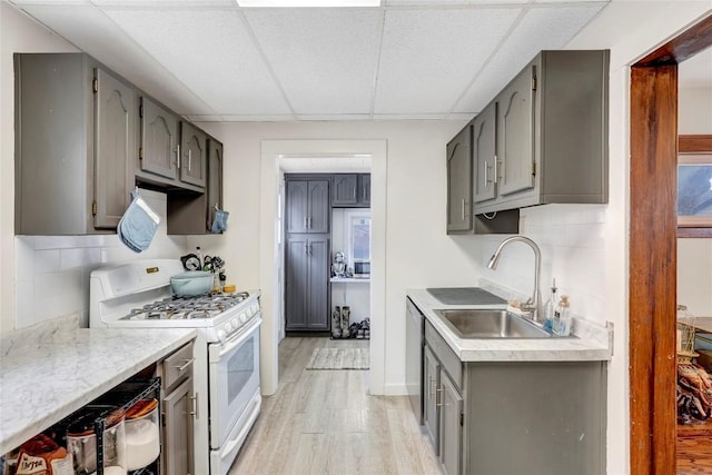 kitchen with white range with gas cooktop, sink, decorative backsplash, and gray cabinetry